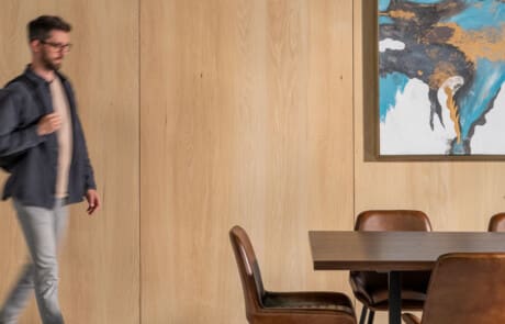 Student Walking to Table In Front Of Red Oak Veneer in Wheat Finish